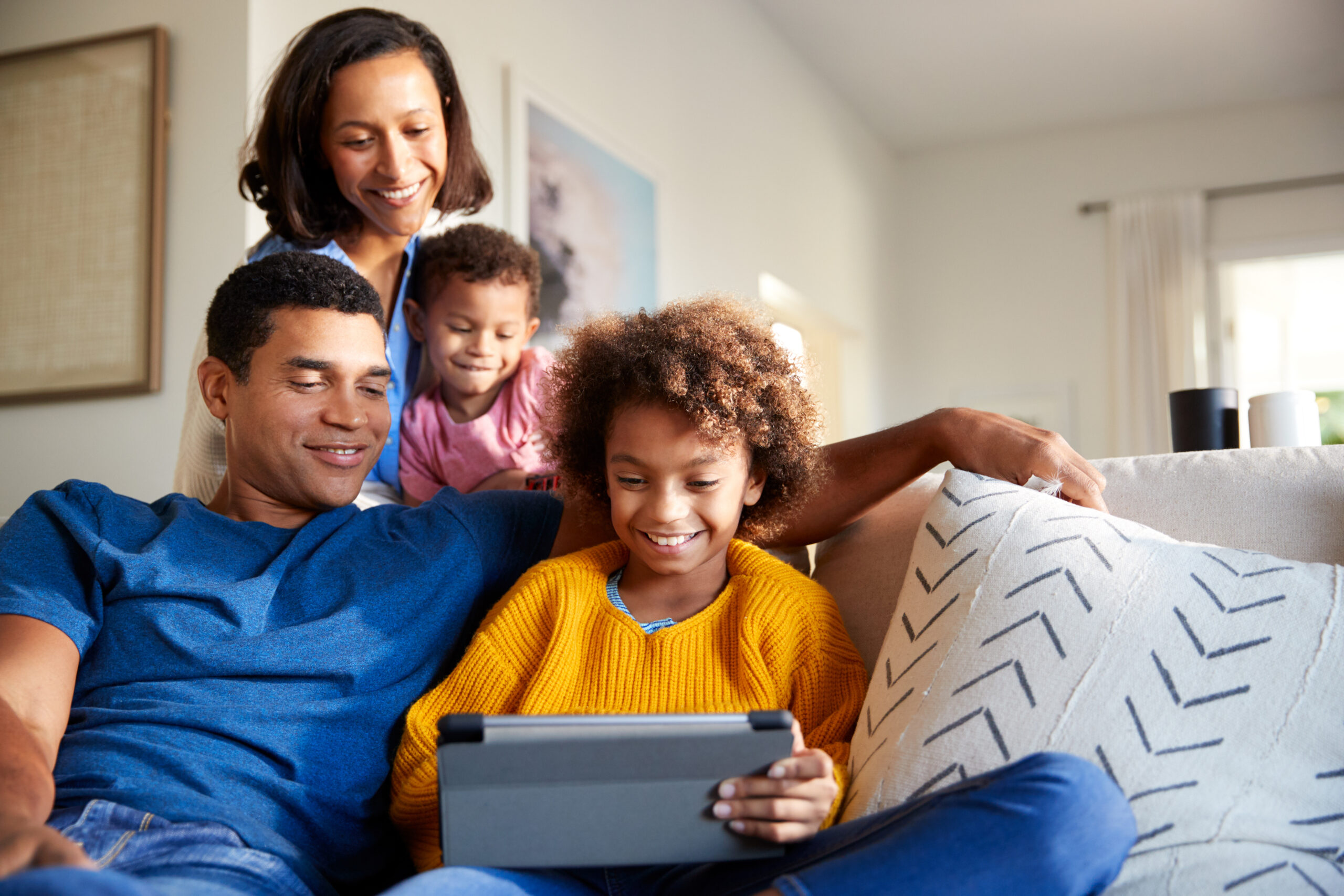 Young family spending time together using a tablet computer in their living room, front view